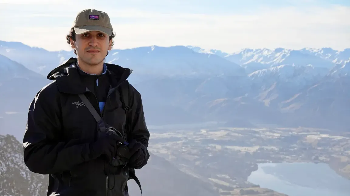 Karim Rahme at a mountain lookout above a lake, with snow-capped peaks in the distance